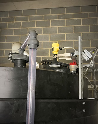 Ein VEGAPULS 64-Radarsensor, montiert über dem Lagertank auf einem Ausleger, misst den Füllstand von Salzsäure durch die Decke des Behälters