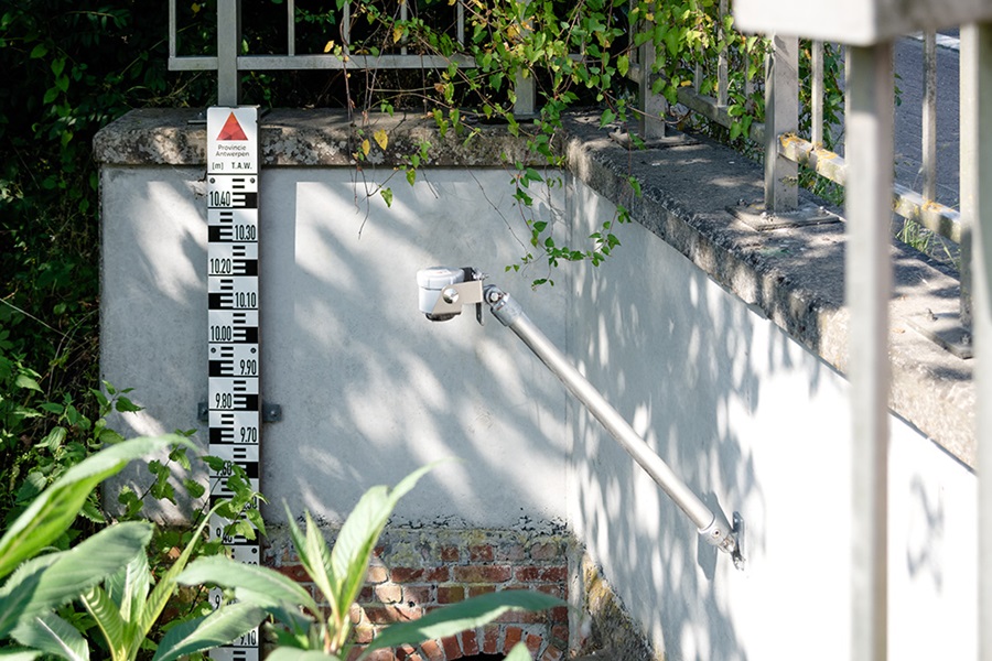 Der VEGA-Radarsensor VEGAPULS Air 41 als moderne Lösung zur Pegelstandsmessung neben einer Pegellatte.